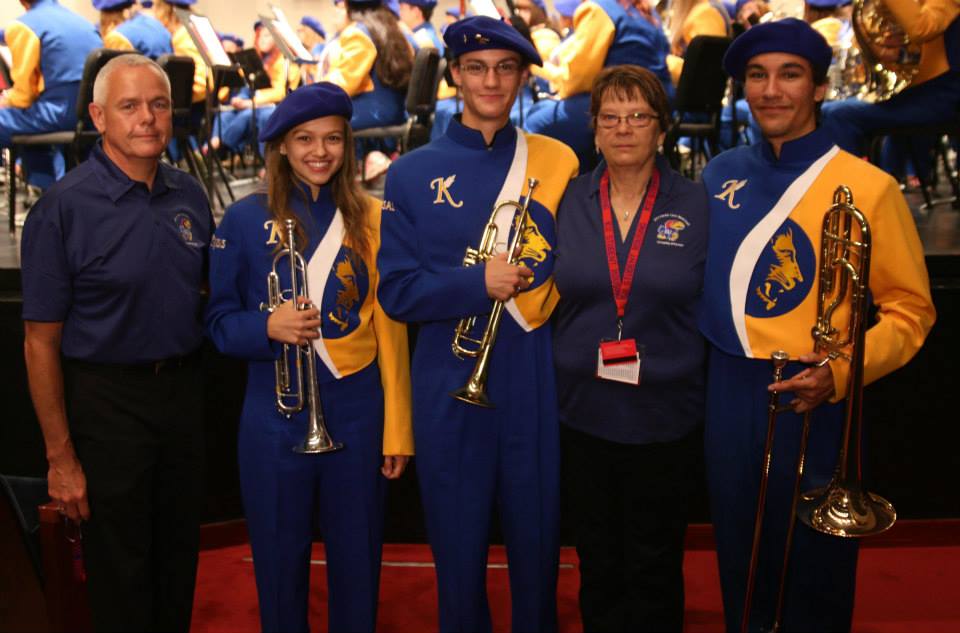 Three musicians wearing their Lions Band uniforms standing with their mentors